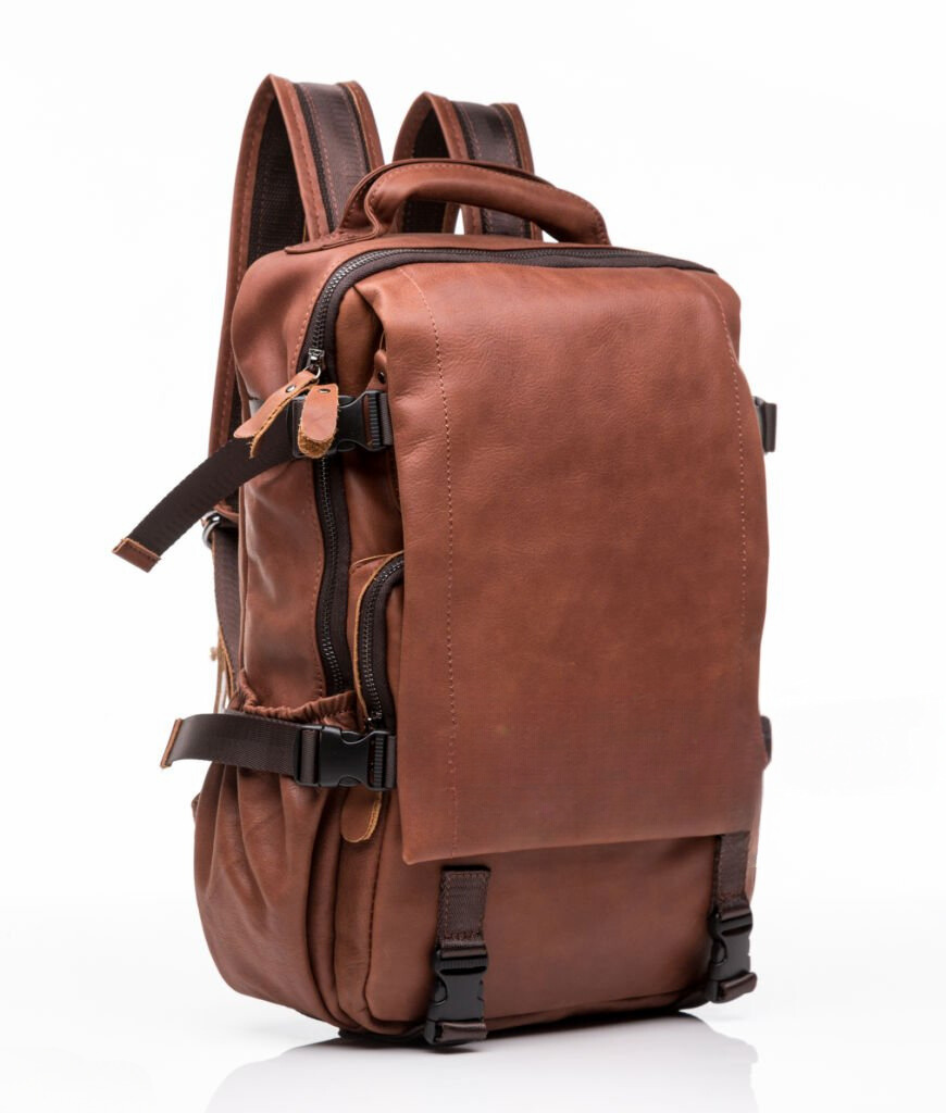 A brown leather backpack with black straps on a white background.